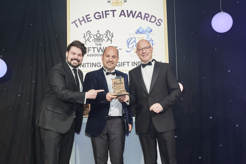 Above: Phil Verrills, (right) sales director of Gift Republic, category sponsor, presented the winning Greats trophy to Greg Rose, co-owner of Maybugs. Comedian and compere Charlie Baker is shown on the left.