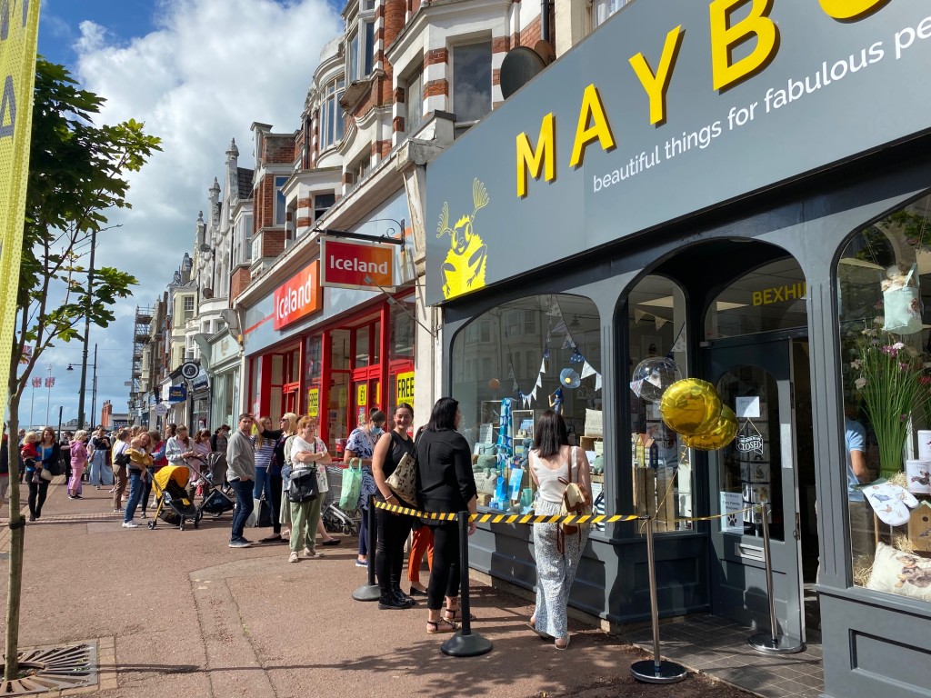 Above: People are shown queuing to shop at Maybugs’ Bexhill-on-Sea store.